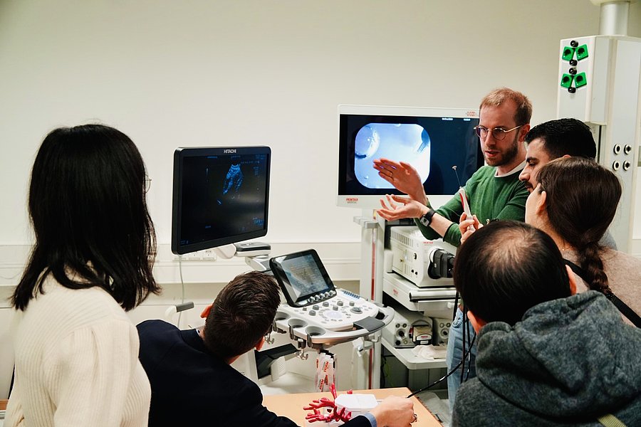 Gruppe von Personen beobachtet eine medizinische Ultraschalluntersuchung auf Monitoren in einem Schulungsraum