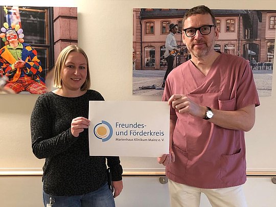 Zwei Personen halten ein Schild mit dem Text 'Freundes- und Förderkreis Marienhaus Klinikum Mainz e.V.'