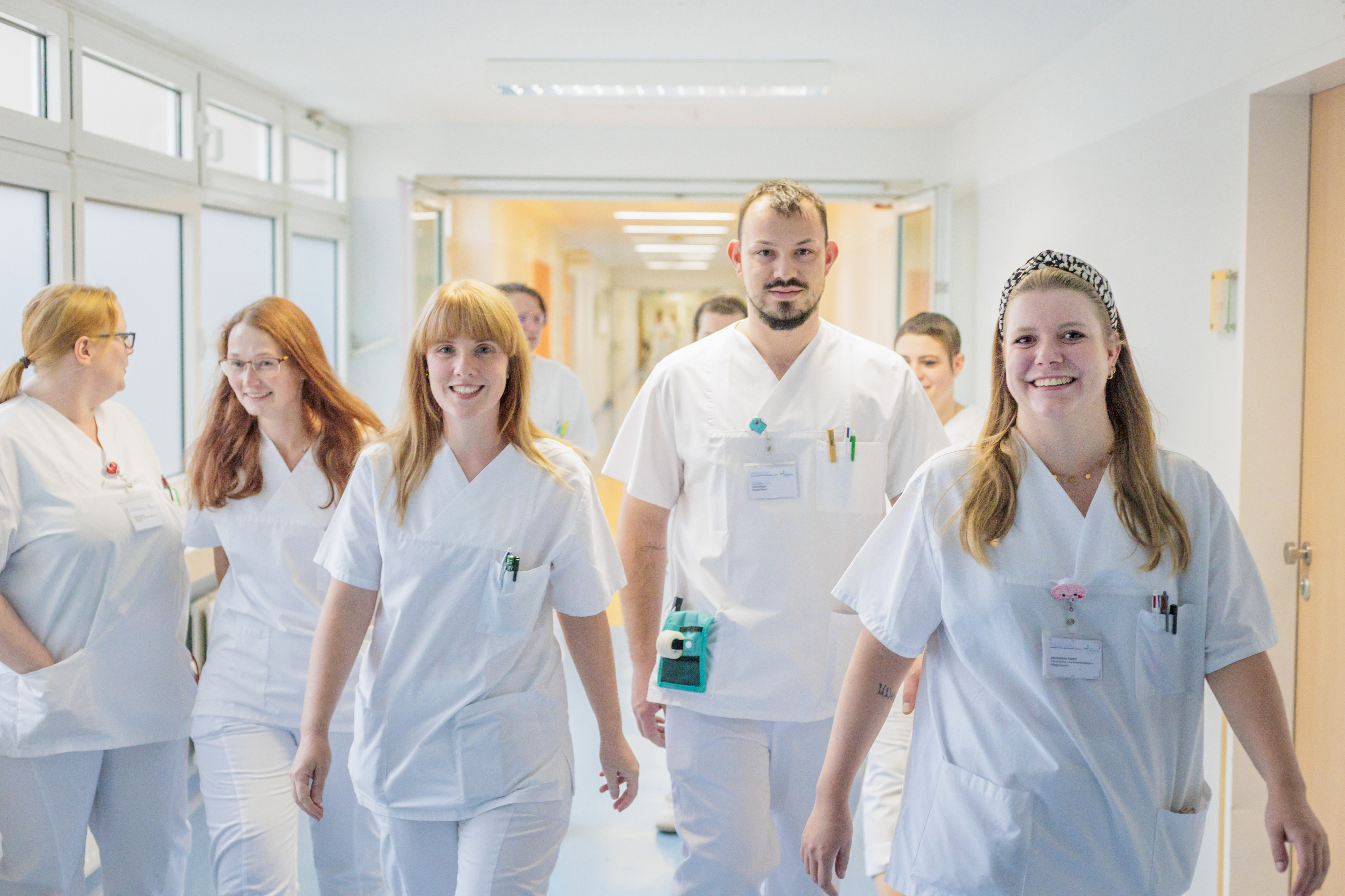 Drei medizinische Fachkräfte in blauer und lila Schutzkleidung arbeiten gemeinsam an einem Patienten mit Beatmungsgerät und medizinischen Monitoren