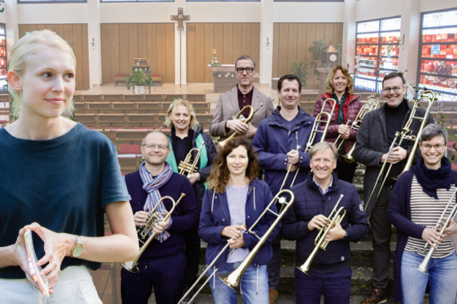 Gruppe von Menschen mit Blasinstrumenten in einer Kirche, vorne eine Person mit verschränkten Händen